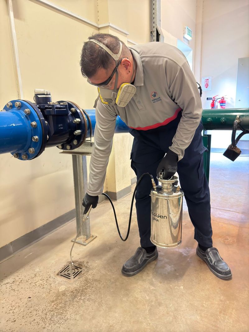 Wipeout technician treating a floor drain in a UAE facility plant room